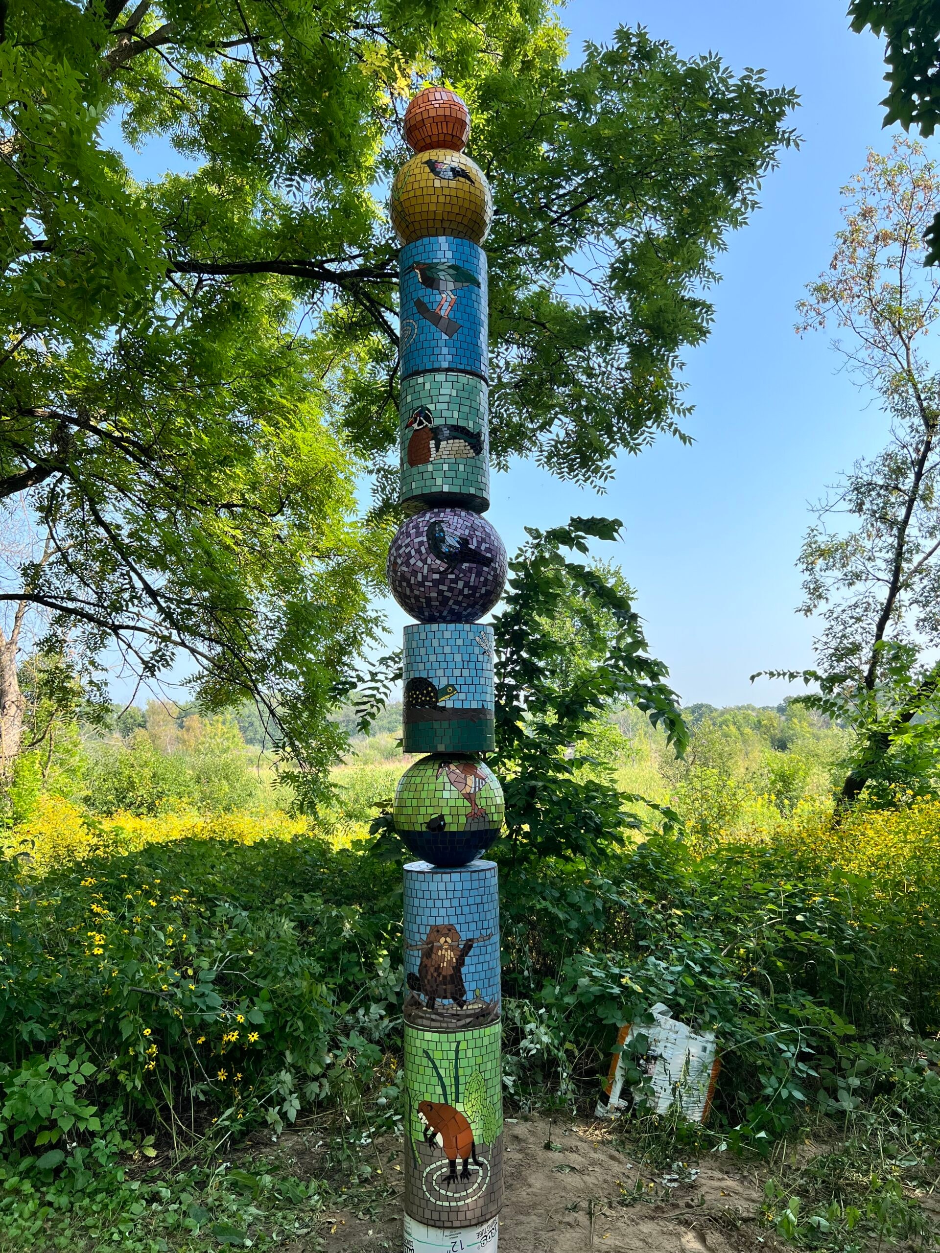 Colorful mosaic totem tower in a natural park setting